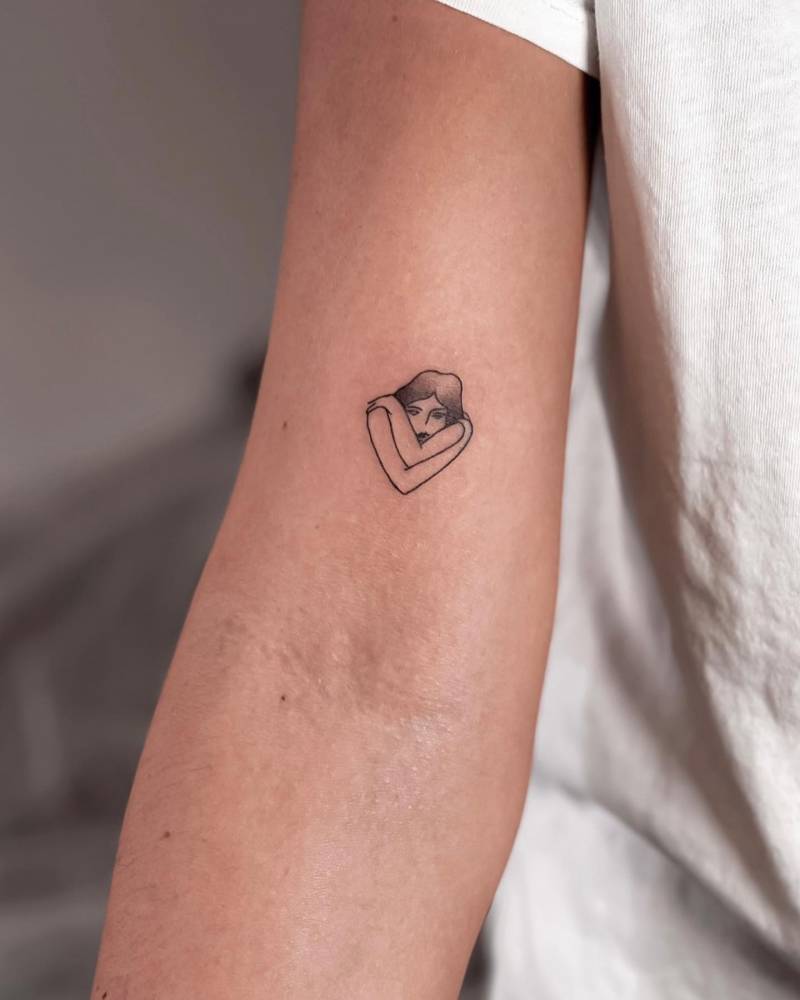 Minimalistic self hug tattoo located on the bicep.