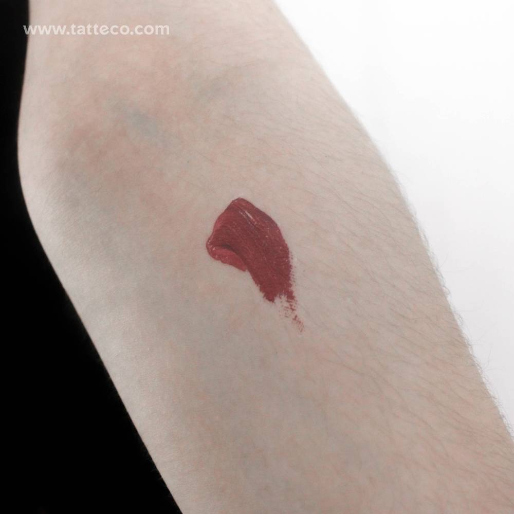 Red brush stroke temporary tattoo located on the inner forearm.