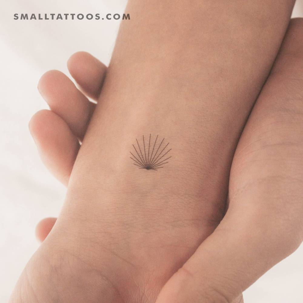 Tiny minimalist scallop shell temporary tattoo located on the wrist.