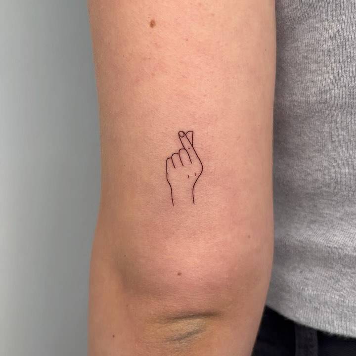 Minimalistic korean finger heart tattoo done on the tricep.