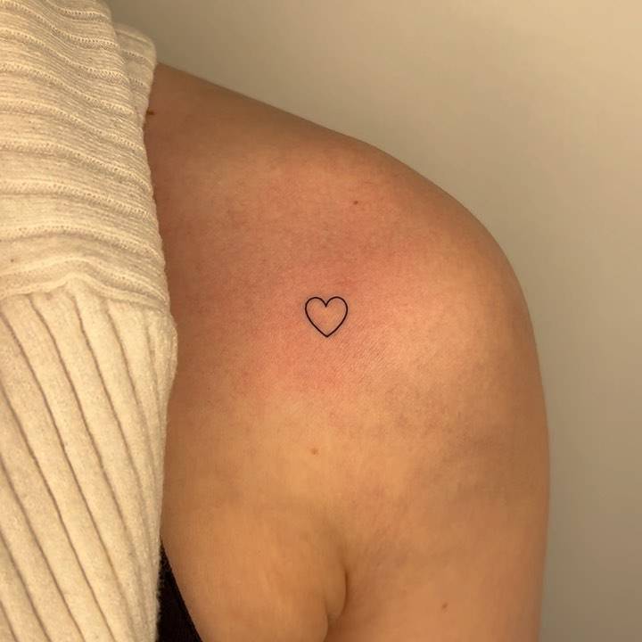 Minimalistic tiny heart tattoo placed on the shoulder.