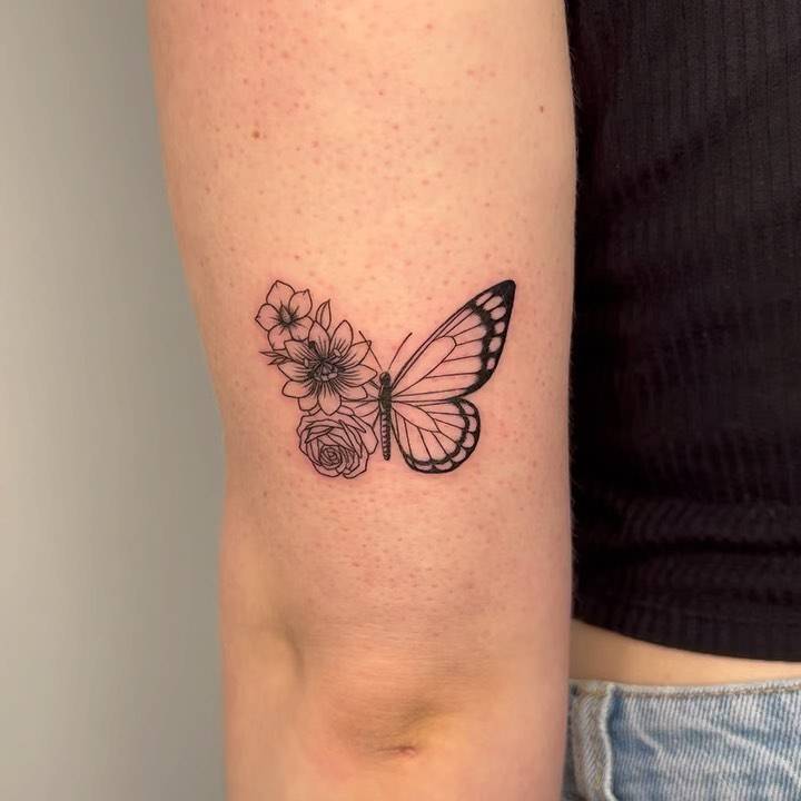 Half butterfly half flower tattoo located on the tricep, illustrative style.