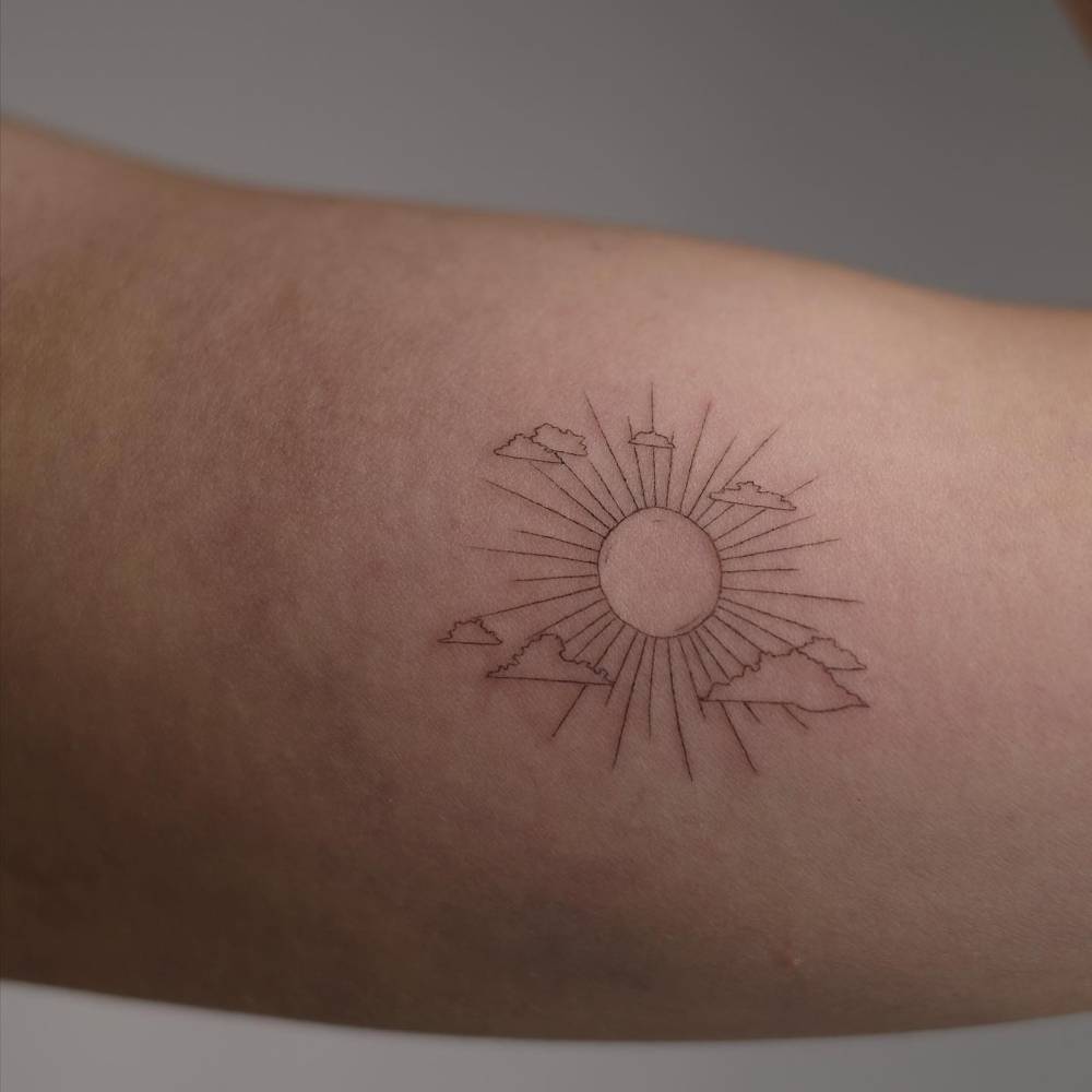 Fine line style sun and clouds tattoo placed on the inner arm.
