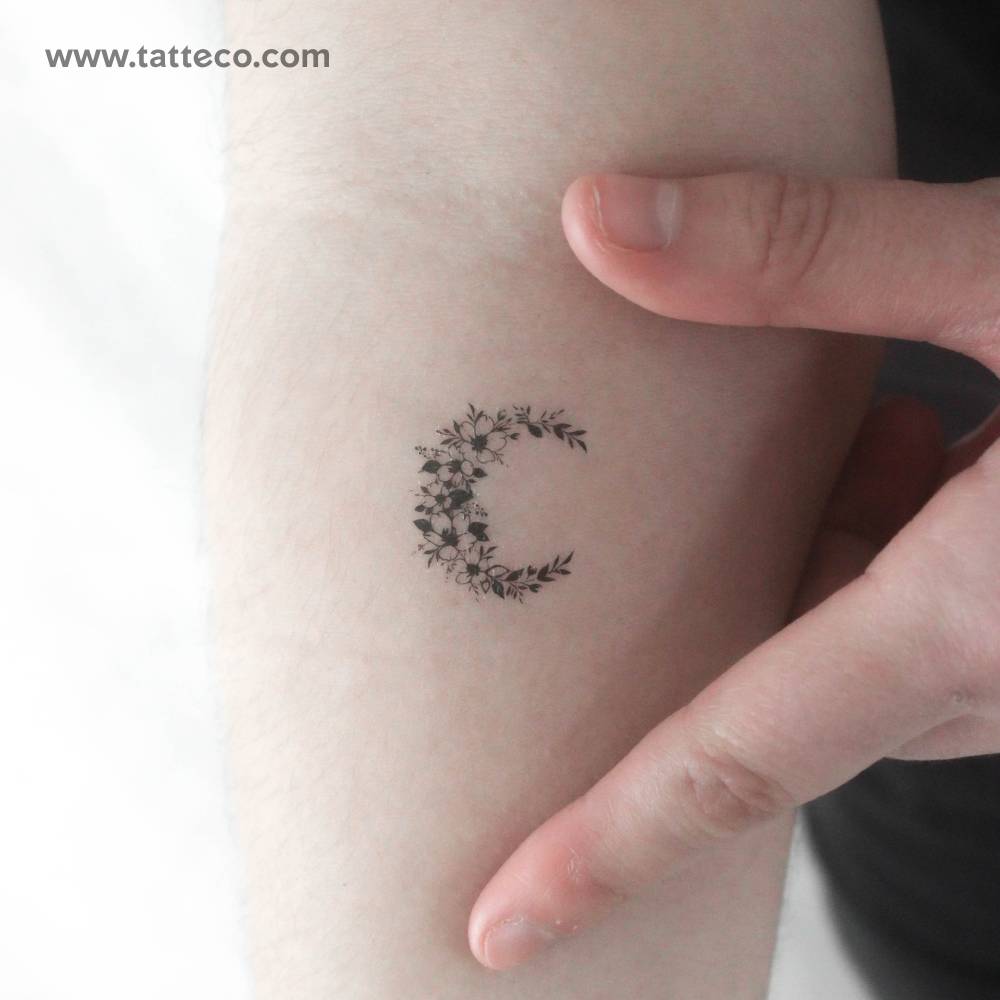 Small flower crescent temporary tattoo located on the inner forearm.