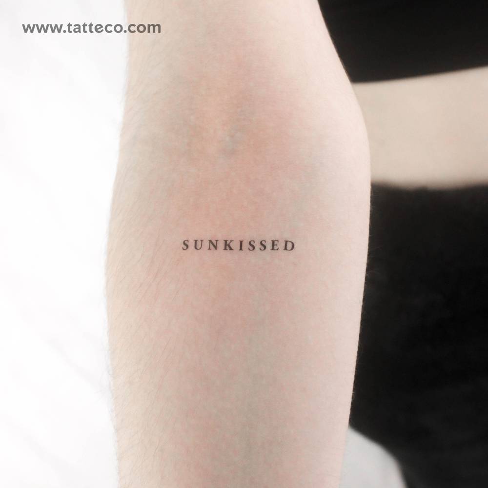 Serif font word "sunkissed" temporary tattoo located on the inner forearm.