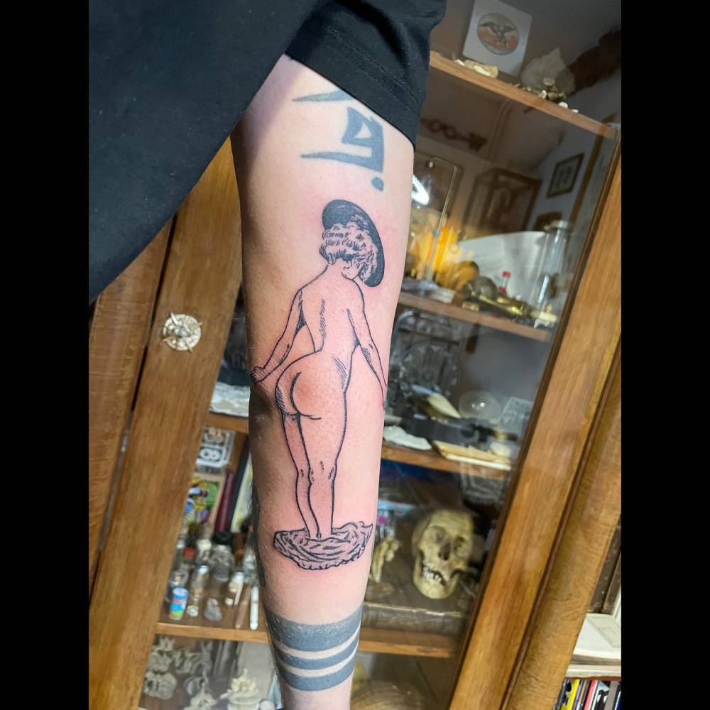 Nude woman tattoo in engraving style located on the arm.