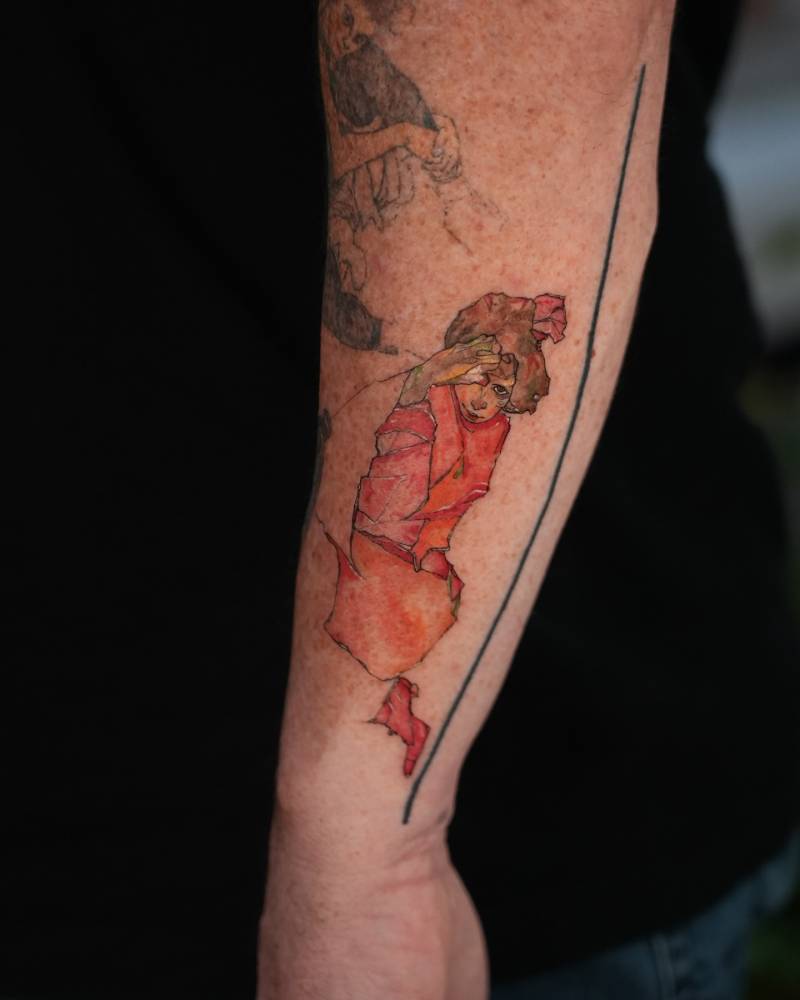 'Kneeling Female in Orange-Red Dress' tattoo located on the forearm.