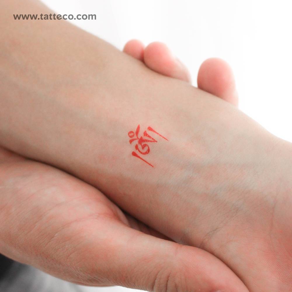 Red Tibetan Om temporary tattoo located on the wrist.