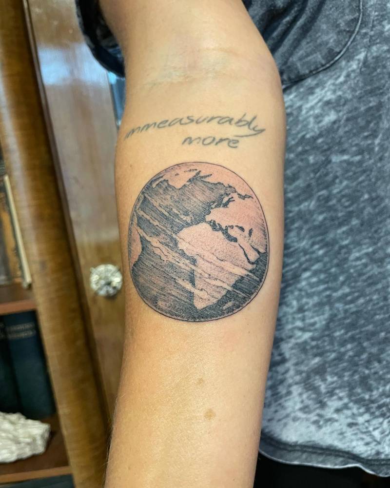 Planet Earth tattoo in illustrative style located on the inner forearm.