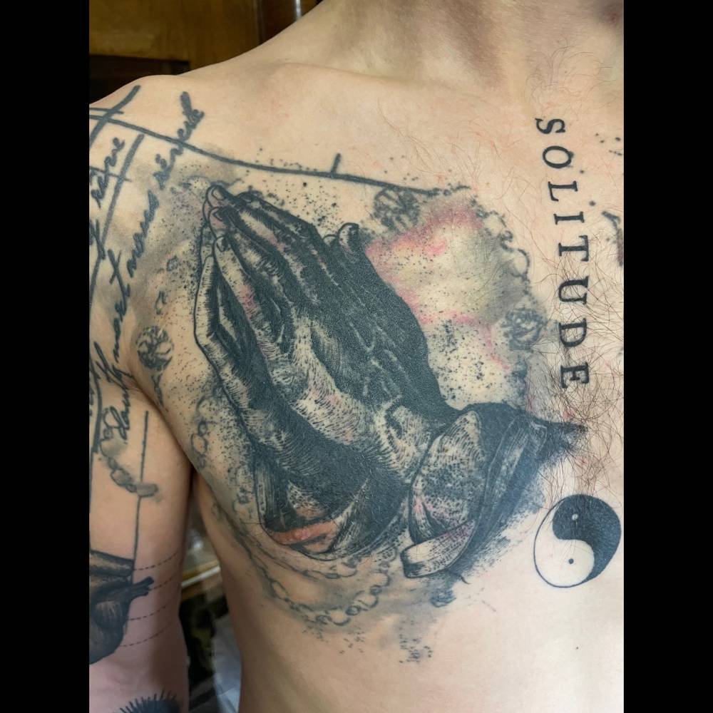 'Praying Hands' tattoo in watercolor style placed on the chest.