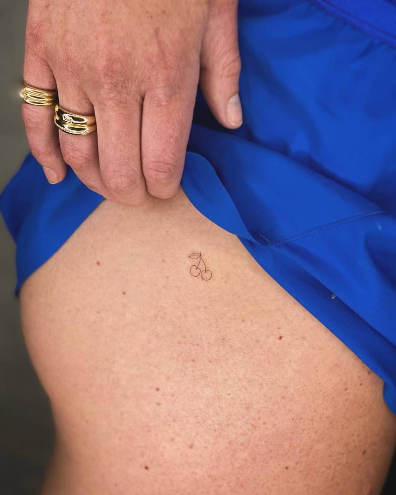 Tiny minimalistic cherries tattoo located on the hip.