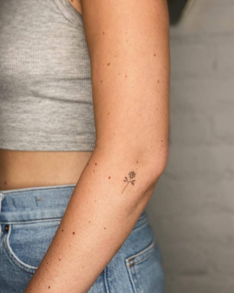 Fine line style rose tattoo located on the elbow.