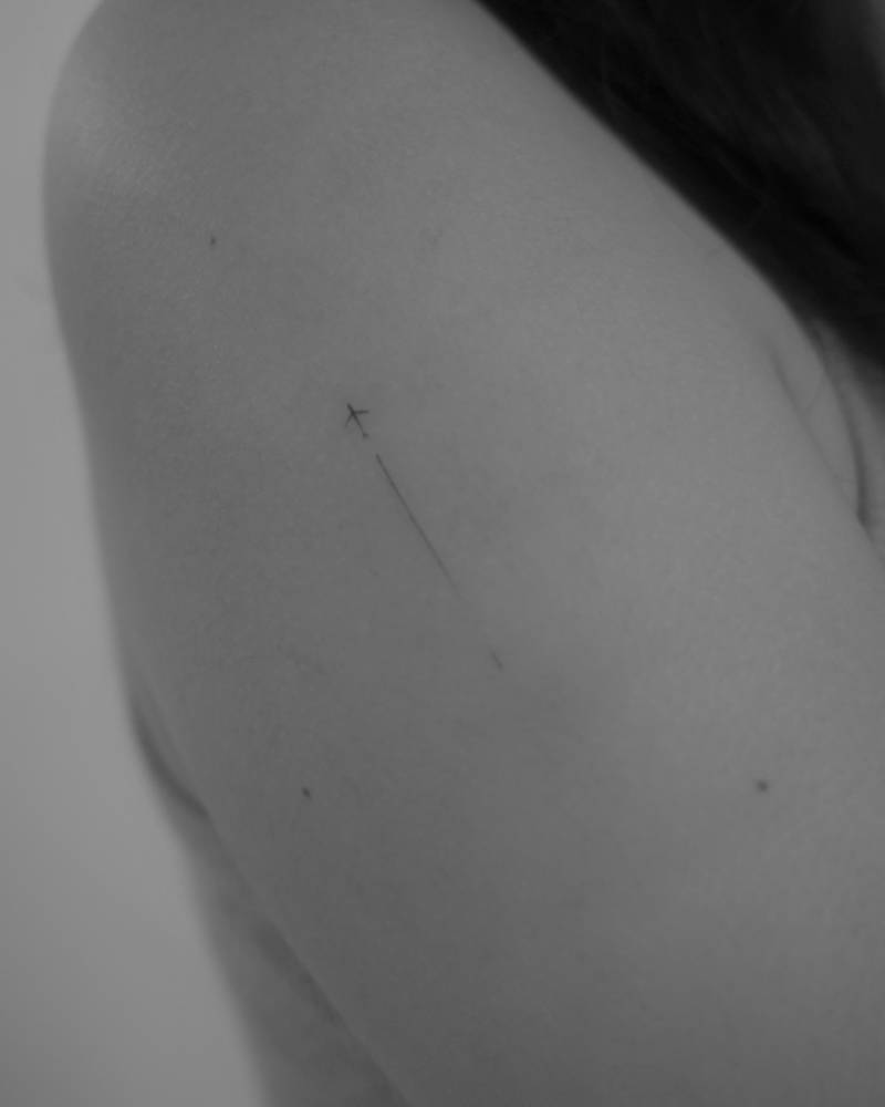 Minimalistic style airplane tattoo located on the upper arm.