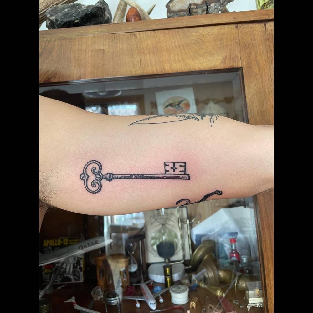 Engraving style key tattoo located on the inner arm.