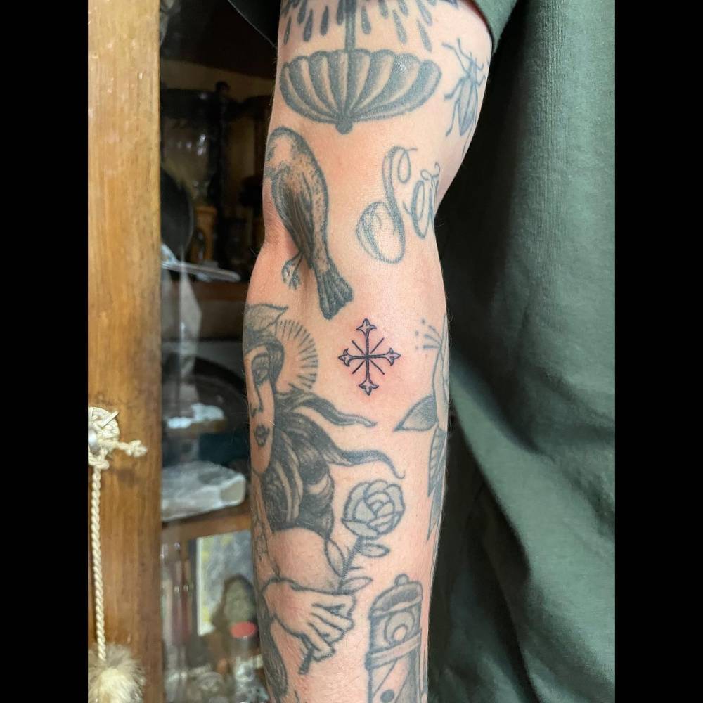 Little cross gap filler tattoo located on the forearm.