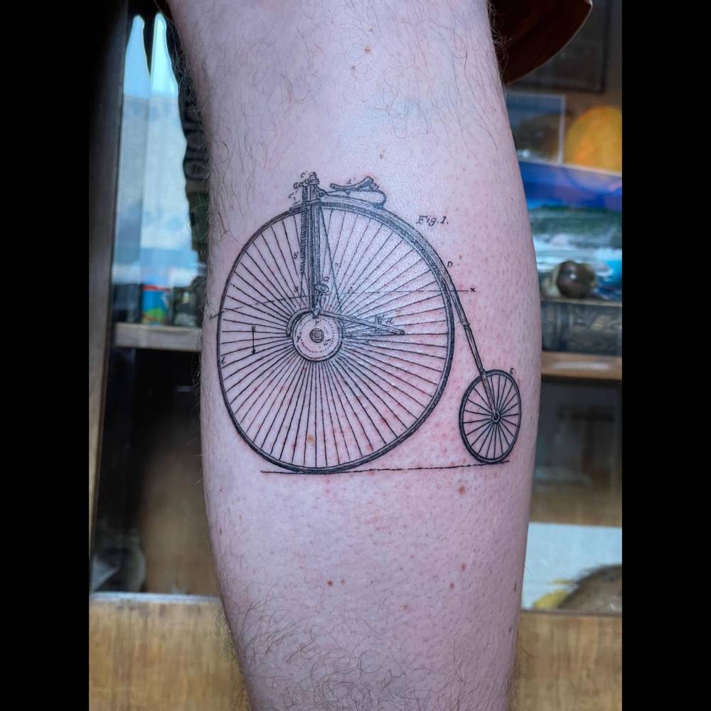 Penny farthing technical drawing tattoo located on the calf.