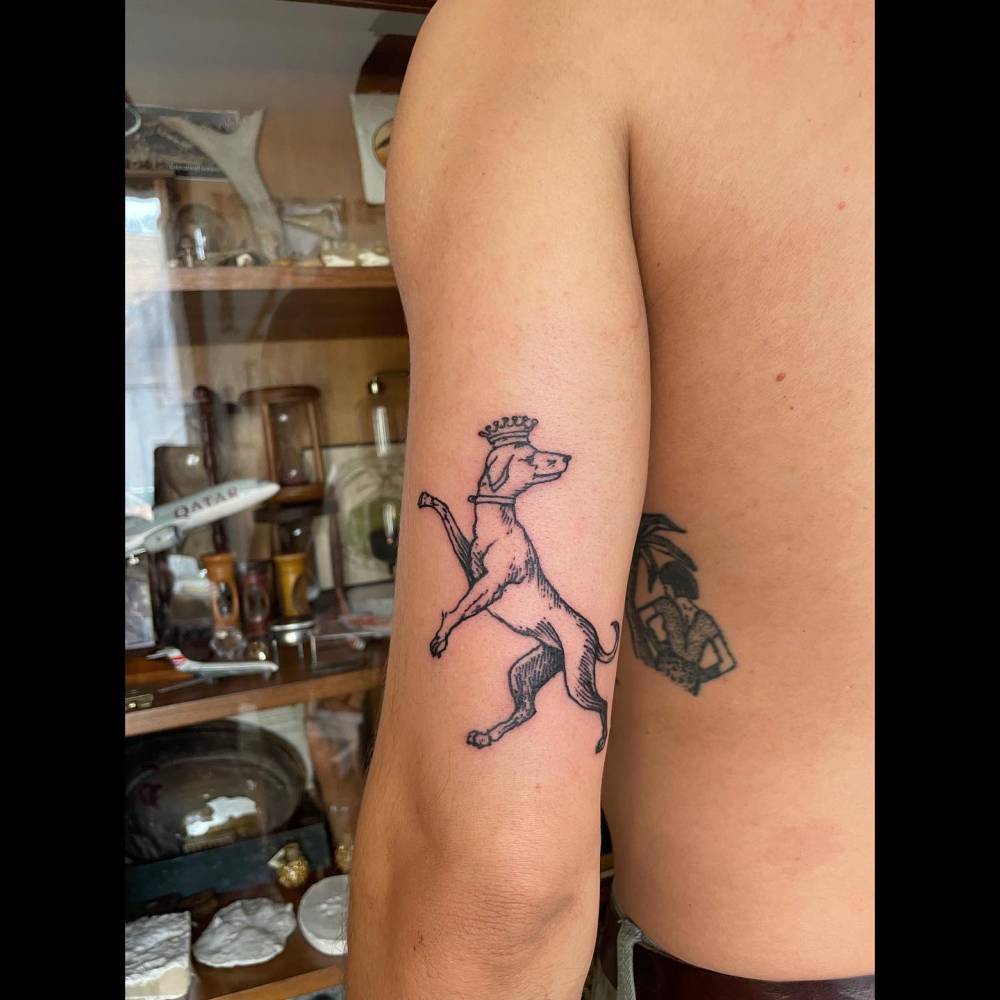 Engraving style dog tattoo located on the tricep.
