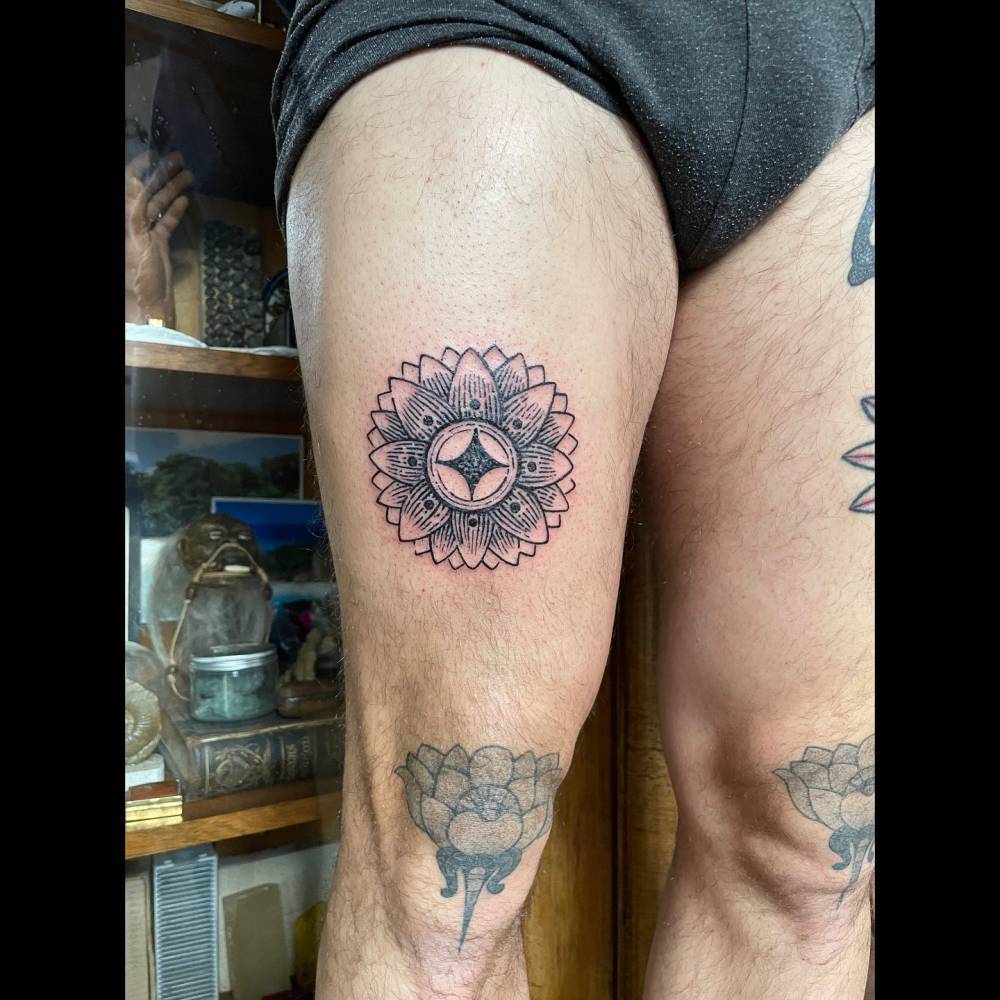 Lotus flower tattoo in engraving style located on the thigh.