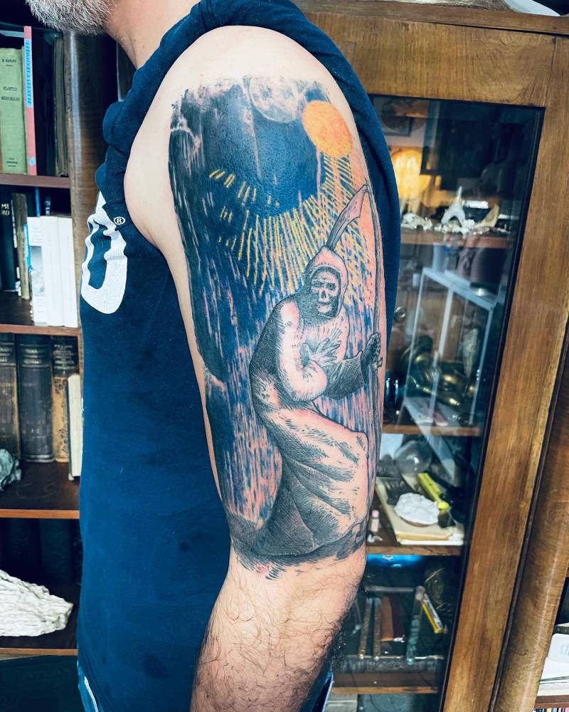 Grim Reaper tattoo in graphic style located on the upper arm.