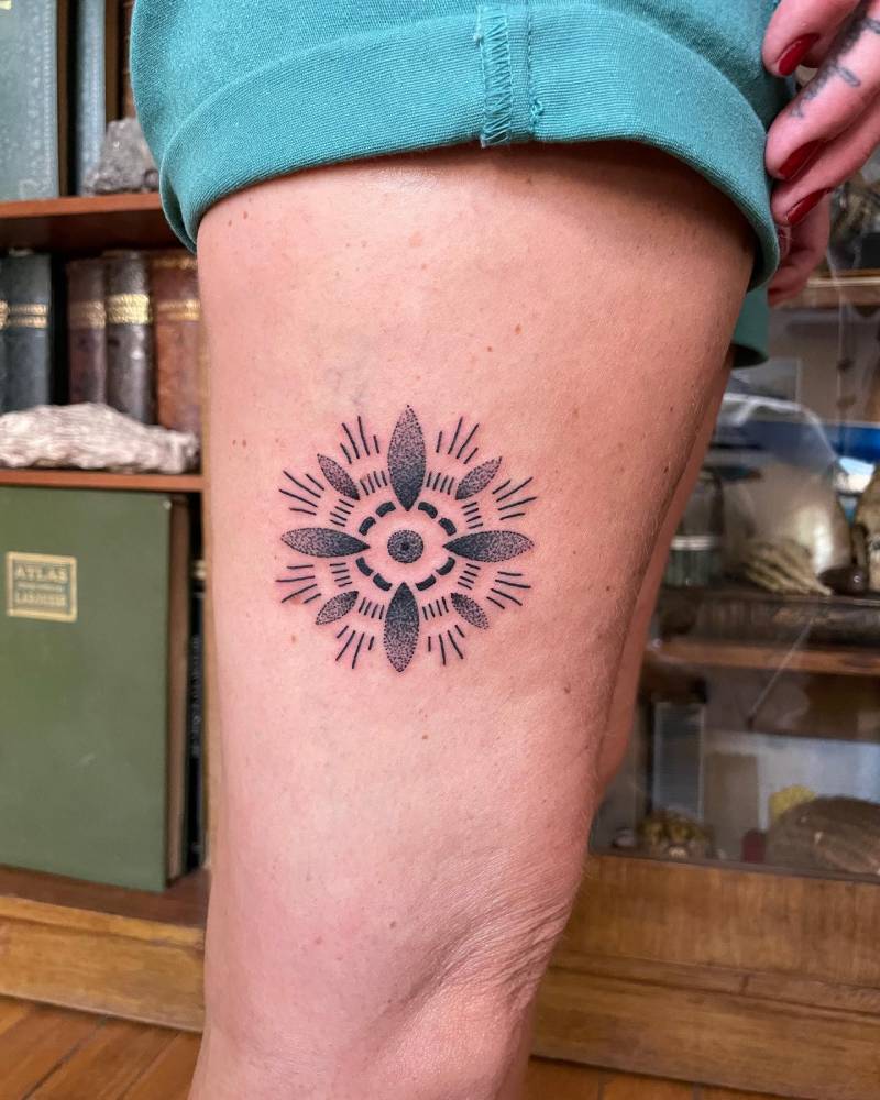 Ornamental flower tattoo in blackwork style located on the thigh.