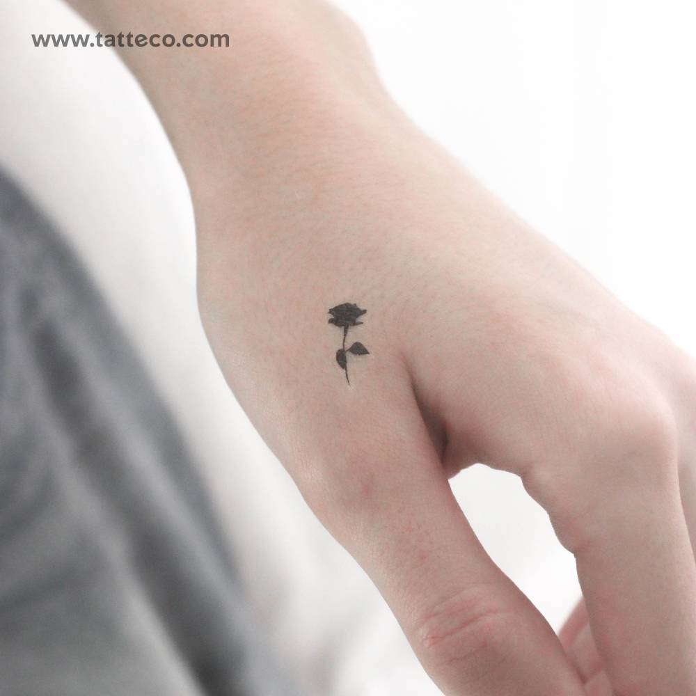 Tiny minimalistic black rose temporary tattoo placed on the hand.