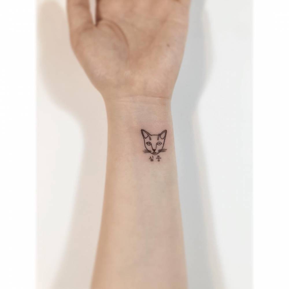 Cat portrait tattoo done on the wrist, minimalistic style.