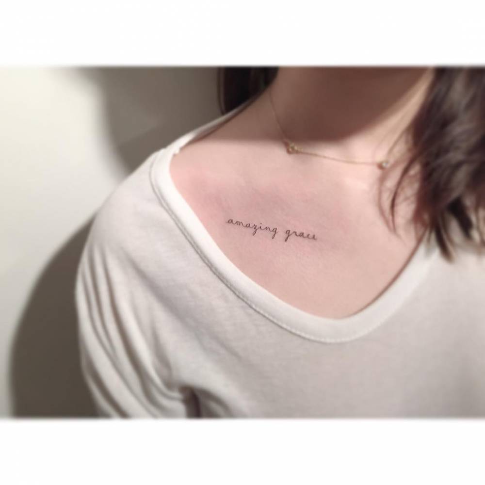 Handwritten font "amazing grace" lettering tattoo done on the collarbone.
