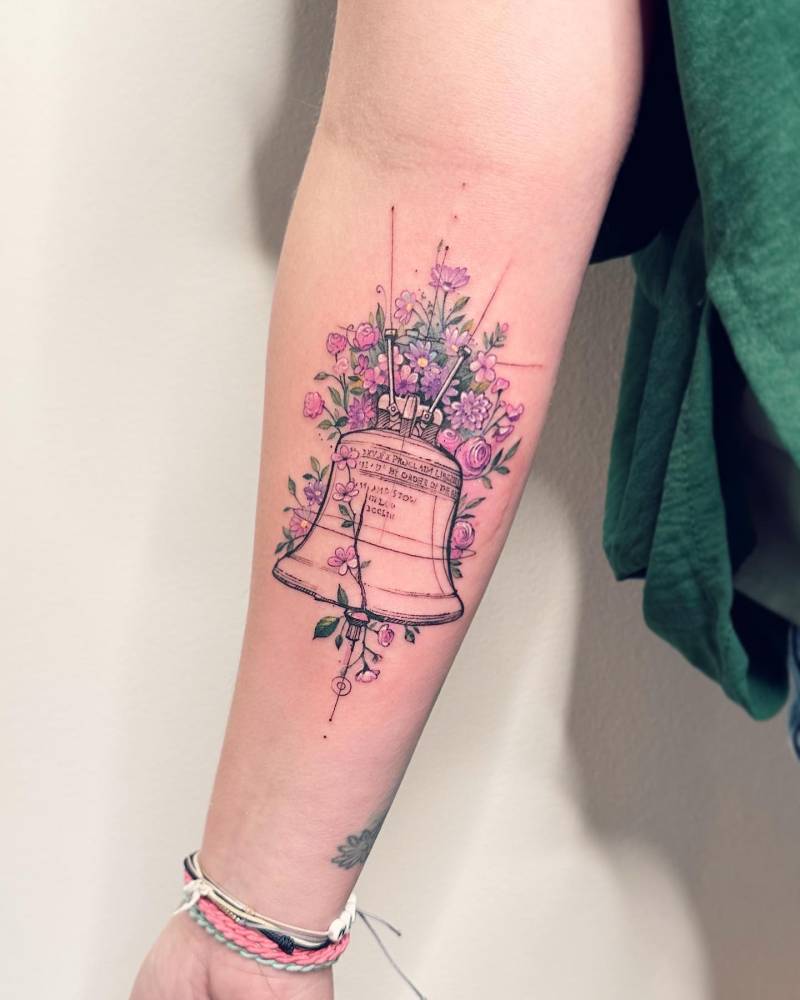 Liberty Bell tattoo in watercolor style located on the inner forearm.