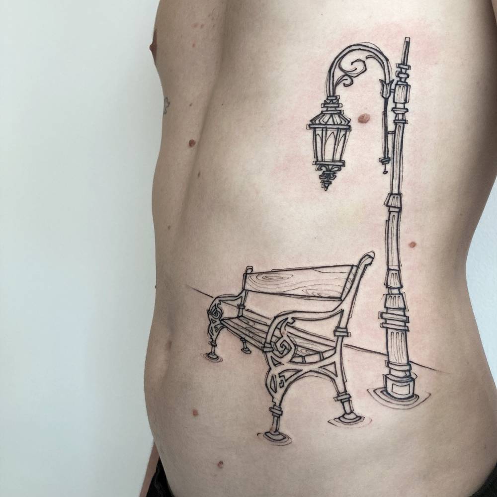 Bench and streetlight tattoo located on the rib, sketch work style.
