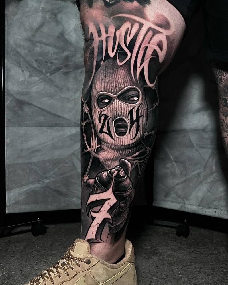 Black and grey "Hustle" tattoo located on the leg.