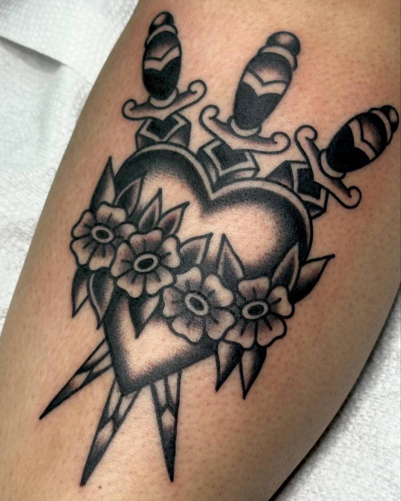 Heart and daggers tattoo located on the calf, traditional style.