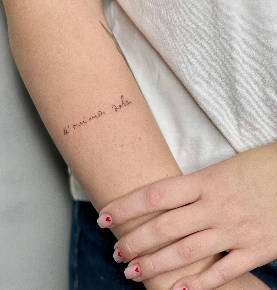 Italian quote tattoo in handwritten font located on the forearm.