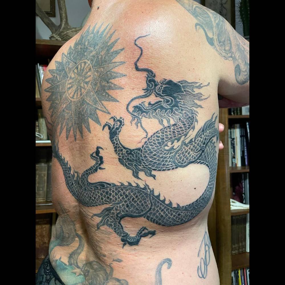 Blackwork style dragon tattoo located on the back.