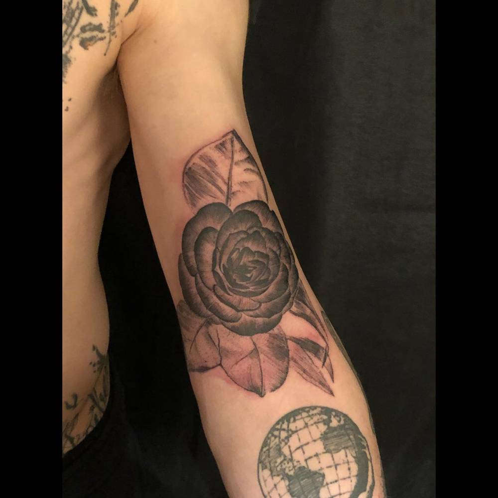 Watercolor style rose head tattoo located on the bicep.