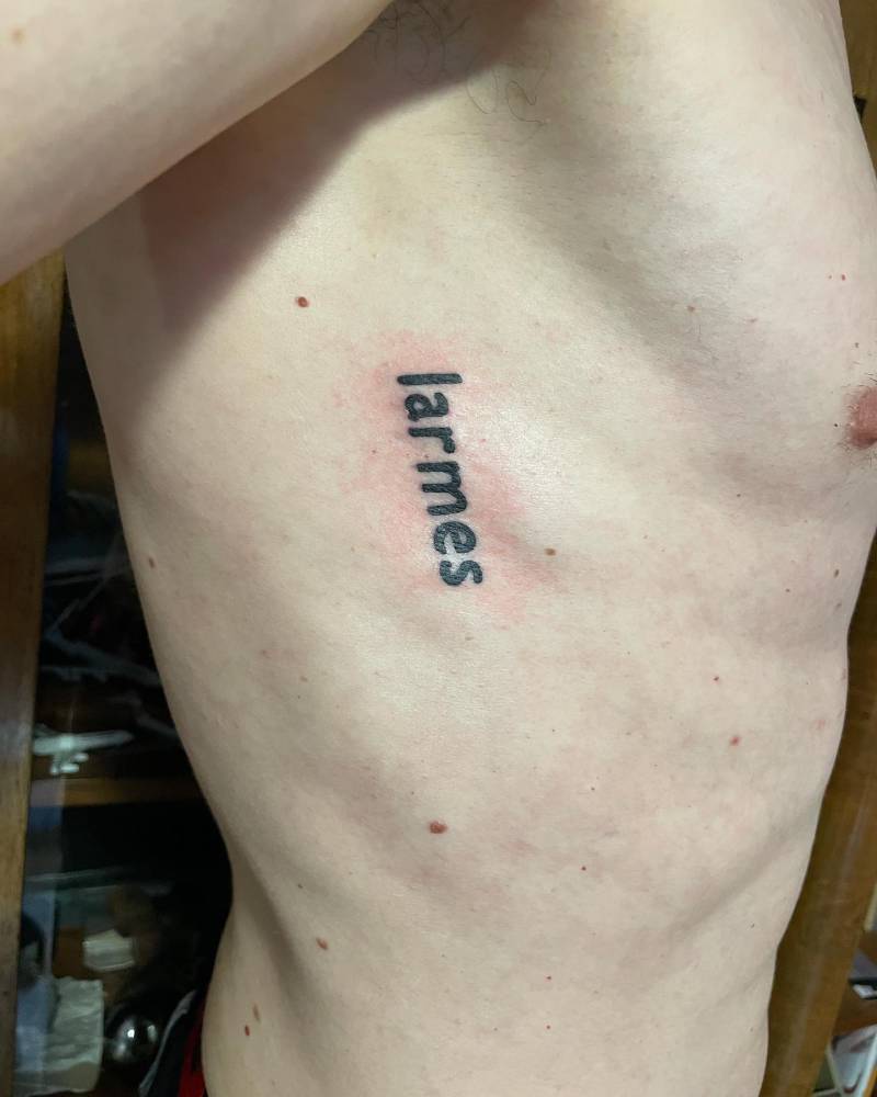 Word "Larmes" lettering tattoo located on the rib.