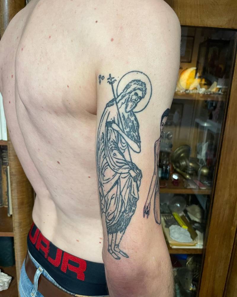 Healed blackwork style saint tattoo located on the tricep.
