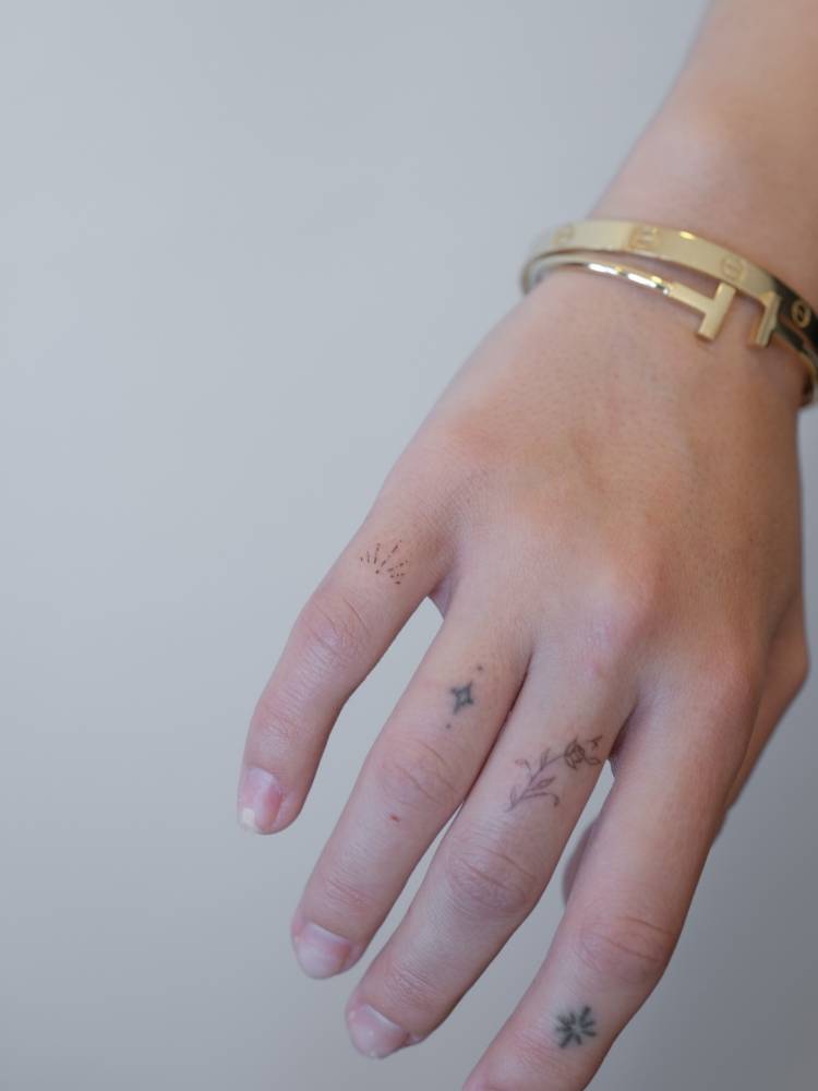 Ornament and tiny flower tattooed on the fingers, fine line style.