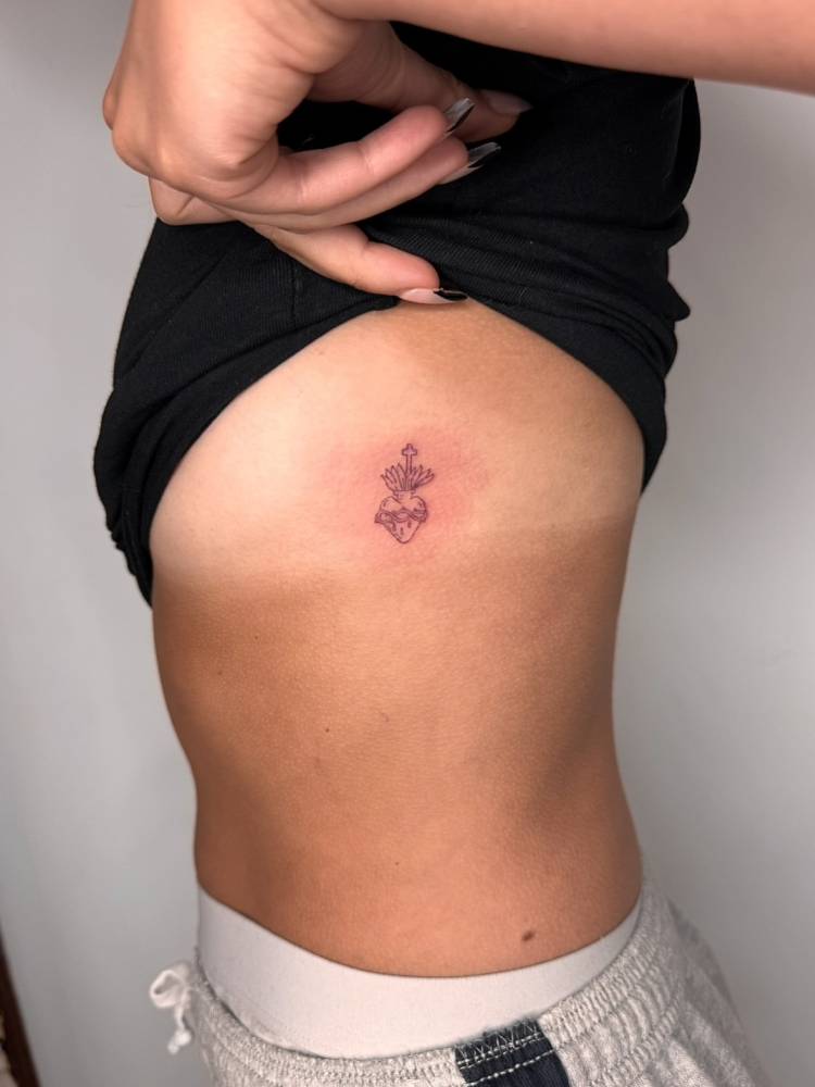 Sacred heart tattoo in fine line style located on the side boob.