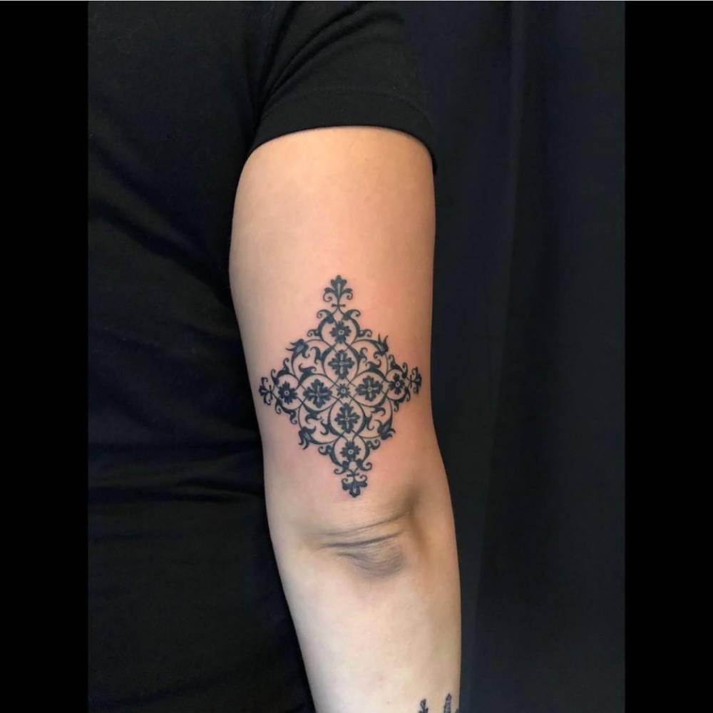 Blackwork style ornamental tattoo located on the tricep.