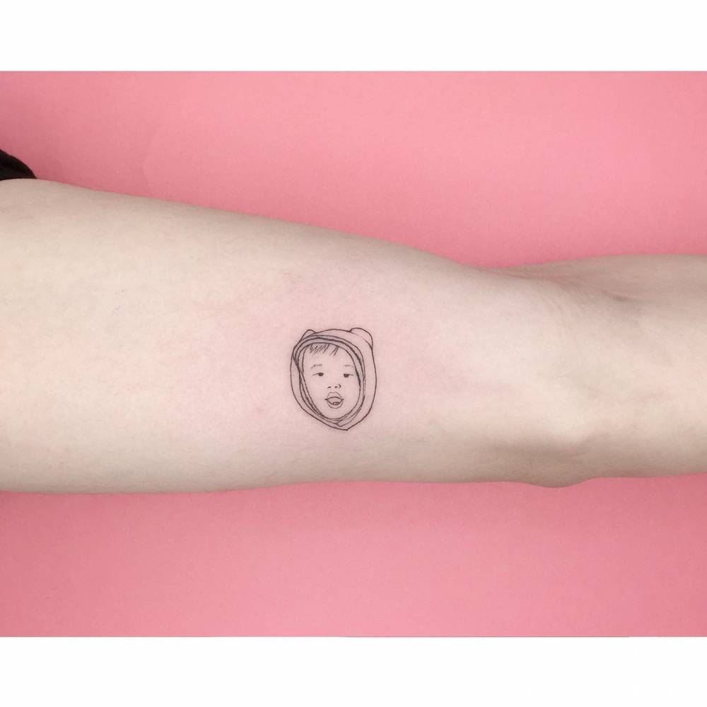 Child portrait tattoo in fine line style located on the inner arm.