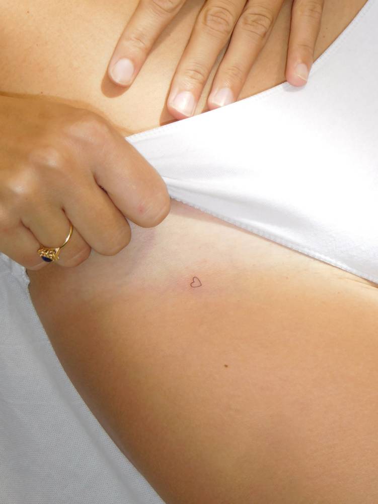 Tiny minimalistic heart tattoo located on the pelvis.
