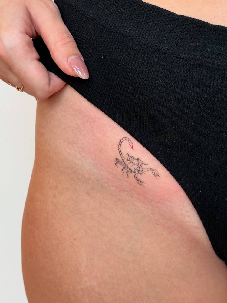 Little fine line style scorpion tattoo placed on the pelvis.