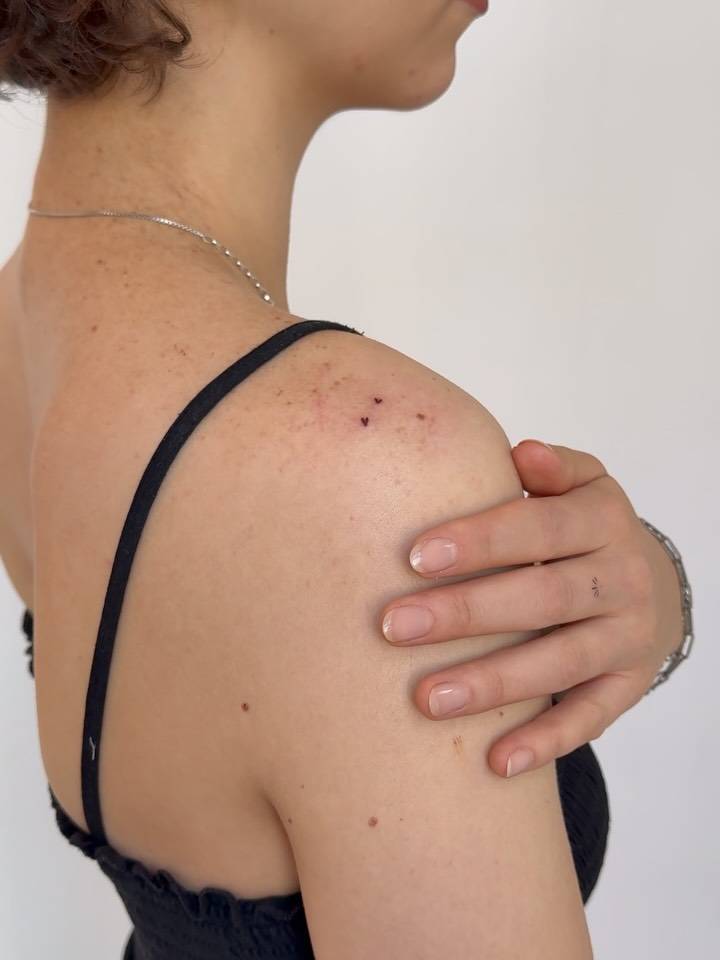 Tiny minimalistic hearts tattooed on the shoulder.