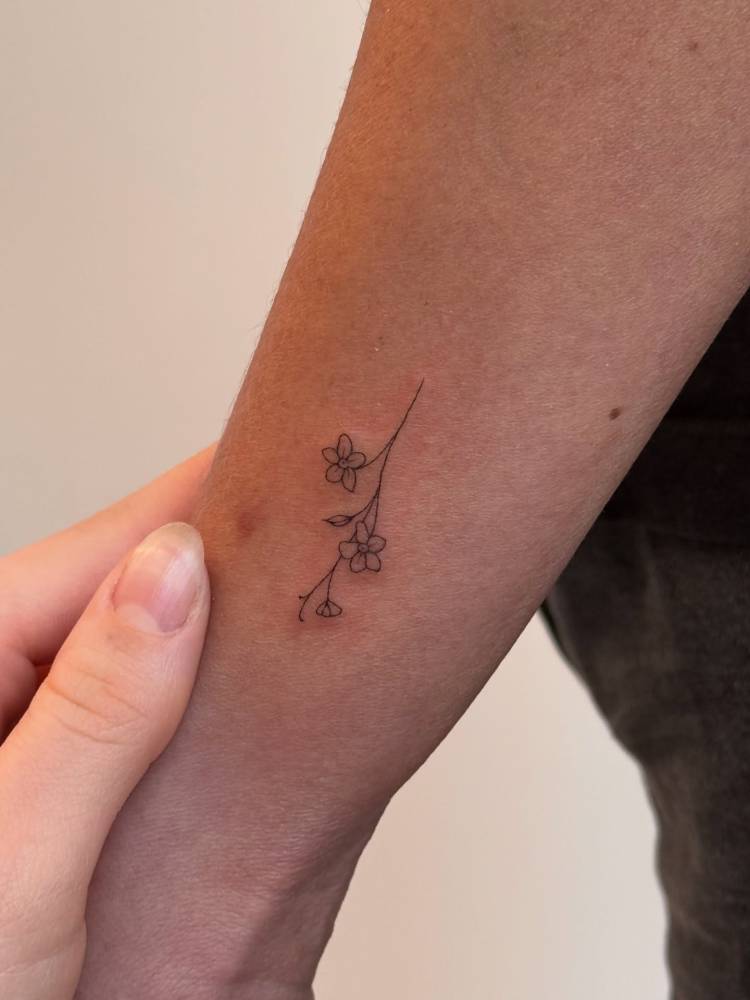Minimalistic style forget-me-not flowers tattooed on the wrist.