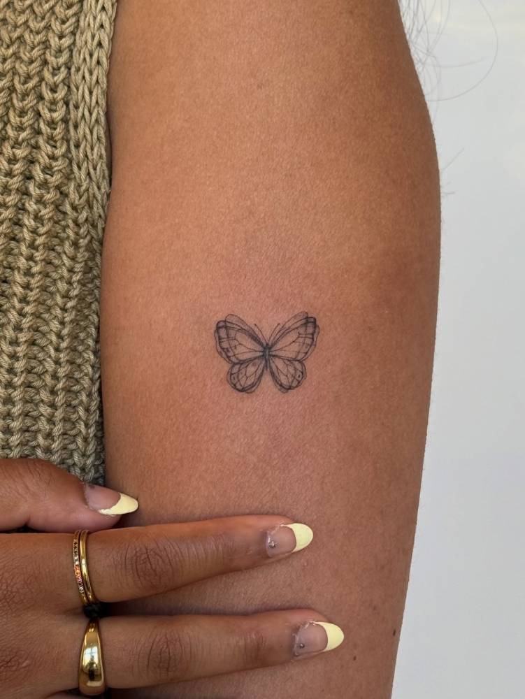 Sketch work style butterfly tattoo done on the upper arm.