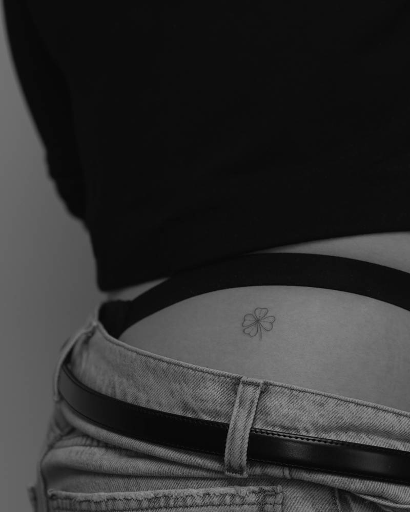 Four leaf clover tattoo in minimalistic style located on the hip.