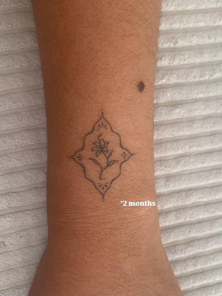 2 months healed fine line style ornamental flower tattoo located on the wrist.