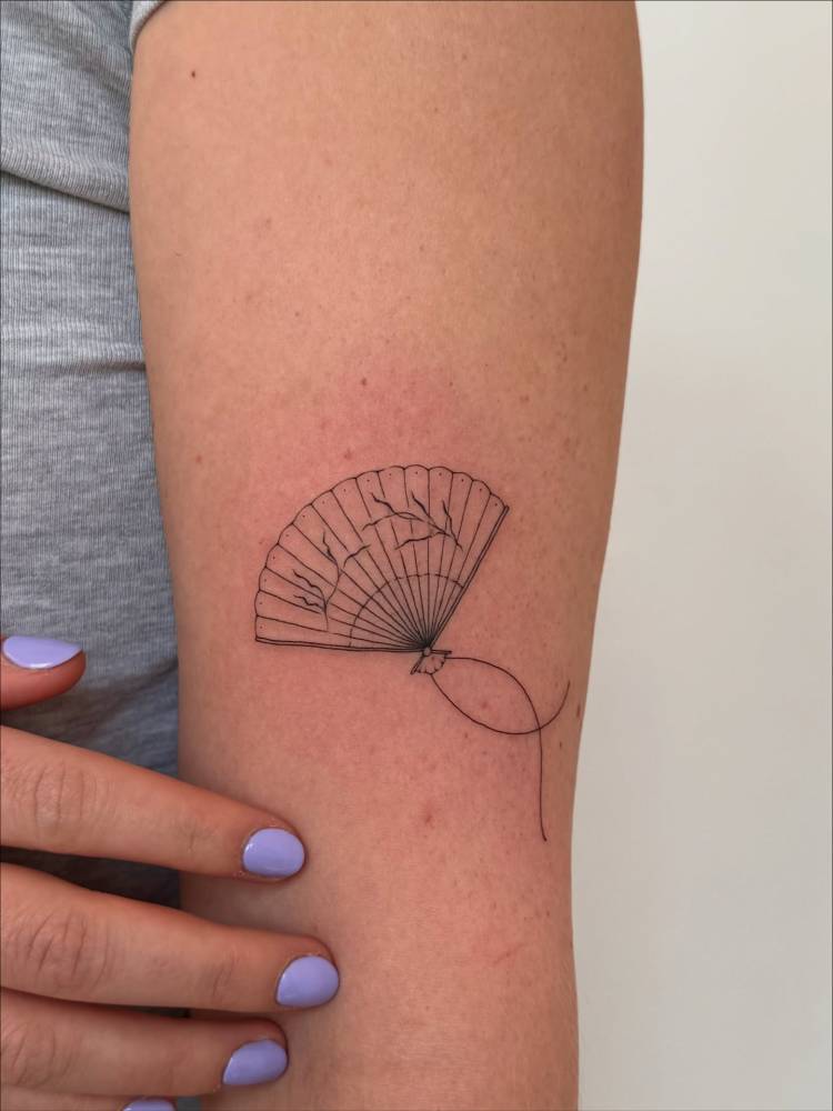 Hand fan tattoo located on the forearm, done in fine line style.