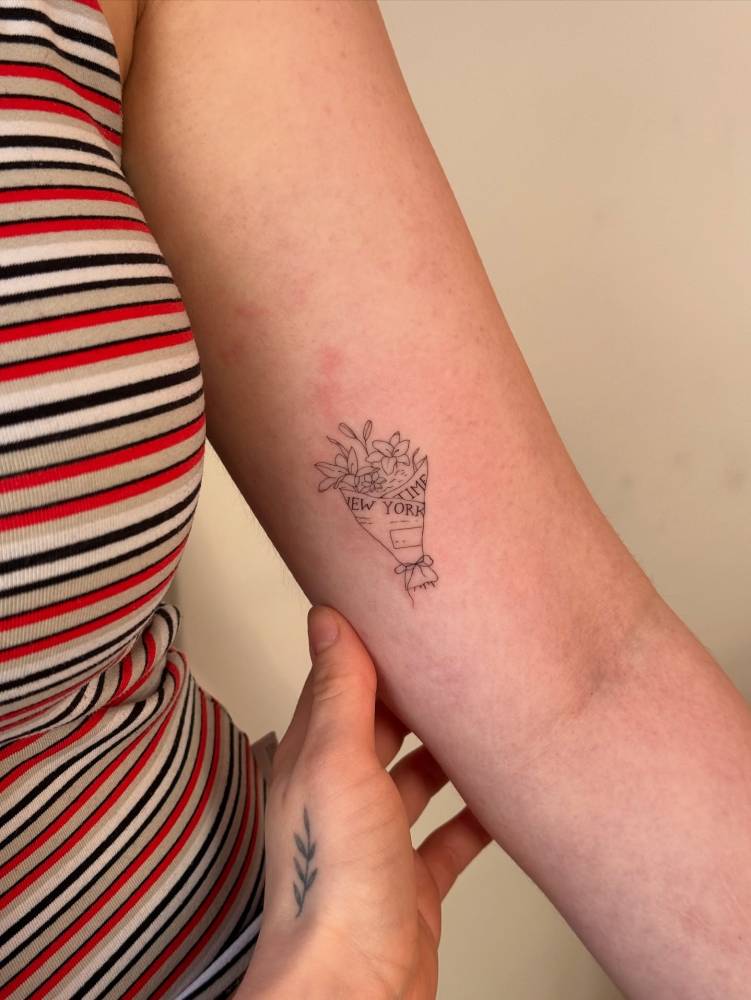 Flower bouquet tattoo in fine line style located on the inner arm.