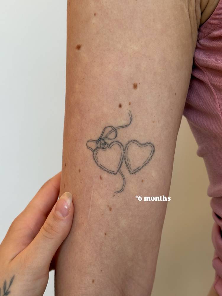 6 months healed heart pendant tattoo located on the inner arm.